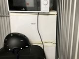 a suitcase and a helmet sitting on top of a refrigerator
