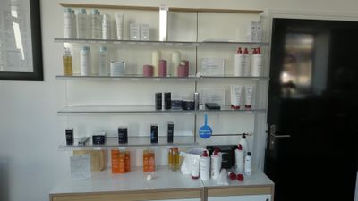 de nombreux flacons de produits capillaires posés sur une étagère dans une pièce