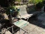 a wooden bench sitting on the sidewalk next to a chair