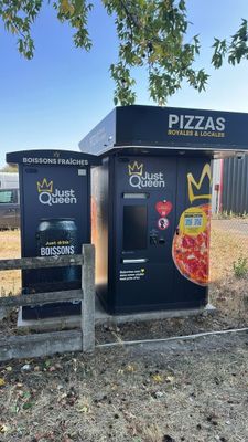 two vending machines that have pizzas on them in front of a fence