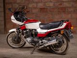 a red and white motorcycle parked in front of a brick wall