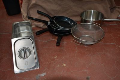de nombreuses casseroles et poêles posées les unes à côté des autres sur le sol
