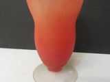 un vase en verre aux couleurs vives posé sur une table blanche devant un mur noir
