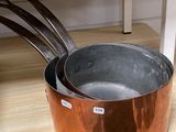 des casseroles et des poêles posées sur une étagère en bois dans une pièce