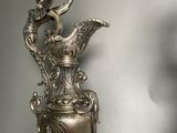 a silver vase with a bird on top of it