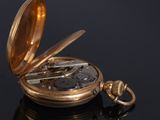 a gold pocket watch sitting on a black surface
