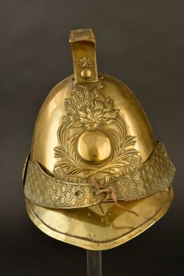 un casque ancien orné de motifs dorés, présenté sur un socle