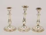 three silver candlesticks are sitting on a white surface