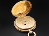 a close up of a gold pocket watch on a black surface