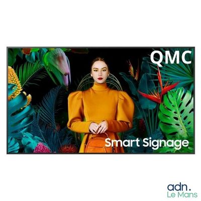 une image représentant une femme debout devant un écran de télévision sur lequel apparaissent les lettres « qmc »