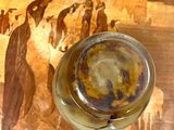 a glass of beer sitting on a table with a painting on it