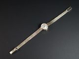 une image représentant une montre-bracelet sertie de diamants, posée sur une surface noire