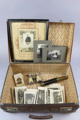 une valise ouverte contenant des photos et un stylo