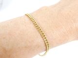 a woman ' s arm with a gold chain bracelet on it