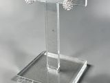 clear acrylic jewelry display stand with a pair of earrings on it