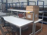 des tables et des chaises dans un entrepôt, avec des cartons empilés dessus
