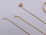 two pairs of gold chains and a ring on a white surface