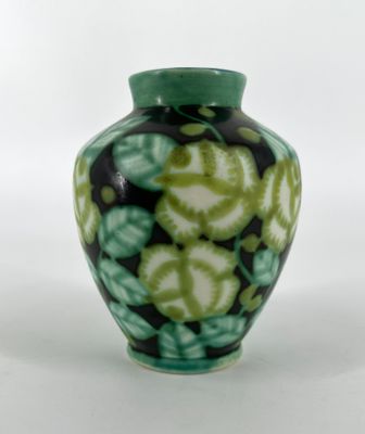 a green and black vase sitting on a white surface