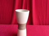 a white vase with a brown band around it