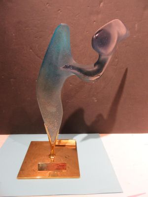 a glass sculpture on a gold plate on a table
