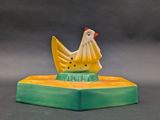 a yellow and green chicken figurine on top of a green base