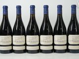 six bottles of wine are lined up on a white surface