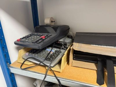 une calculatrice et un ordinateur portable posés sur une étagère dans une pièce