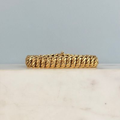 un gros plan d'un bracelet en or posé sur une surface en marbre