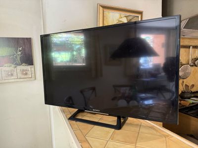 a flat screen tv sitting on a counter in a kitchen
