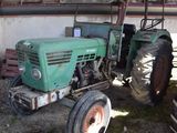 a green tractor parked in front of a building
