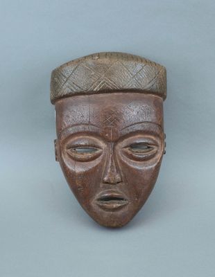 un vieux masque en bois surmonté d'un chapeau