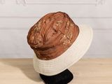 brown and white straw hat on a black stand on a wooden table