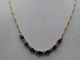 a gold necklace with blue sapphire stones on a mannequin