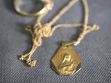 a gold necklace that has a picture of a woman on it