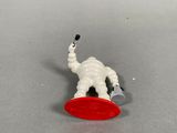 a small toy elephant with a red frisbee in it ' s mouth