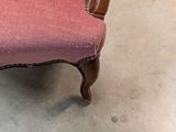 a pink chair with a wooden frame on the floor