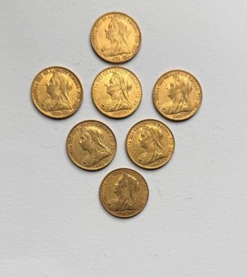 six gold sovereigns are arranged in a triangle on a white surface