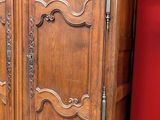 a large wooden cabinet in a room with a red wall behind it