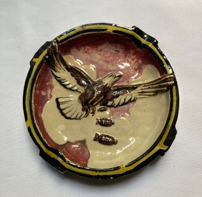 une petite assiette sur laquelle est représenté un oiseau, posée sur une table