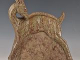 sculpture représentant un cerf sur un rocher, avec un oiseau perché sur son dos