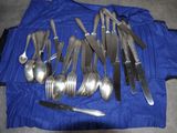 de nombreuses cuillères et fourchettes en argent posées sur une nappe bleue