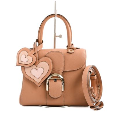beige leather handbag with heart shaped handles and a metal handle