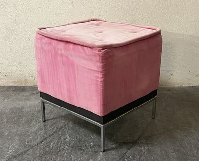 a small pink ottoman sitting on a metal stand