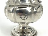 a silver vase with a lid on a white surface