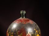 a glass vase with flowers painted on it on a purple surface