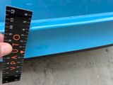 someone is measuring the height of a blue car with a ruler