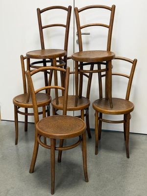 quatre chaises en bois sont empilées les unes sur les autres devant un mur