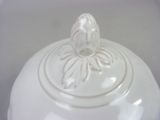 a white bowl with a lid that has a flower on it