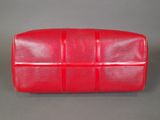 a red louis vuitton clutch bag on a grey background