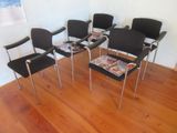 four black chairs in a room with a magazine on the table